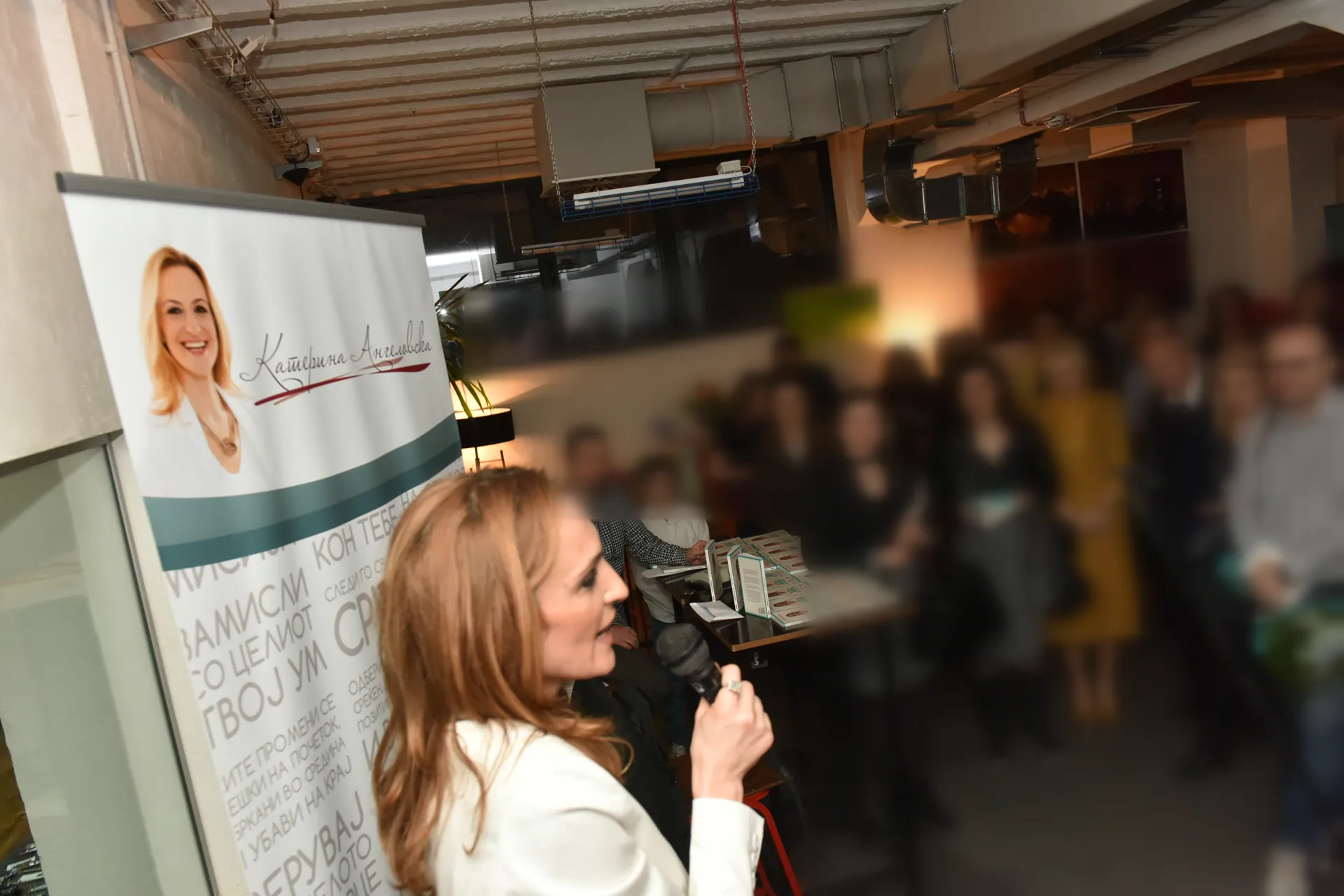 MSc Katerina Angelovska speaking with a microphone in front of an audience